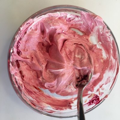 Tigela de vidro com creme rosa e colher metálica