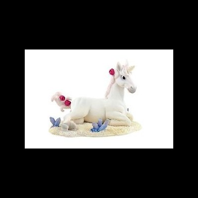 Pelúcia de unicórnio branco com flores cor-de-rosa sobre base de areia com pedras azuis