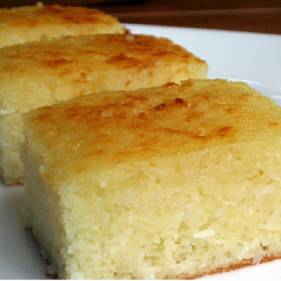 Três quadrados de bolo amarelo claro com crosta dourada em prato branco