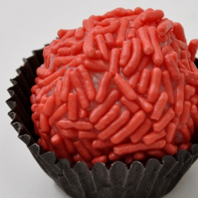 Doce brigadeiro com granulados vermelhos em forminha preta