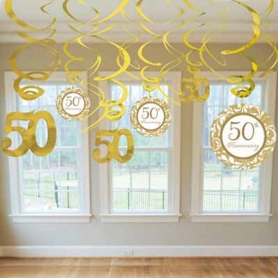 Decoração suspensa dourada com números '50' e círculos com '50th Anniversary' em frente a janelas.