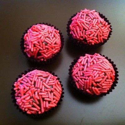 Cupcakes com cobertura de granulado rosa em forminhas pretas