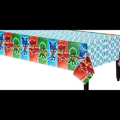 Toalha de mesa com padrão de heróis PJ Masks coloridos sobre fundo azul claro com círculos.