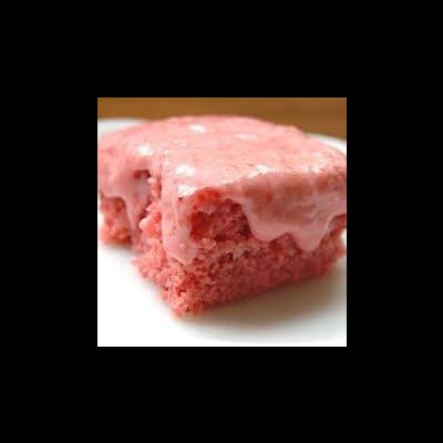 Bolo quadrado cor-de-rosa com cobertura cremosa da mesma cor no prato branco