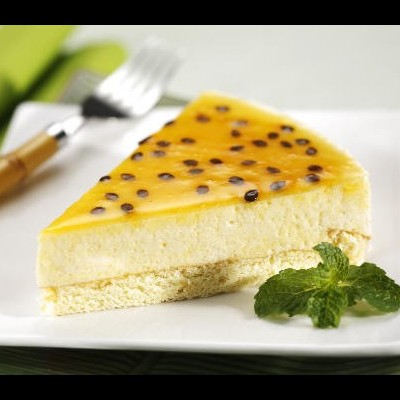 Fatia de bolo de maracujá num prato branco com folhas de hortelã