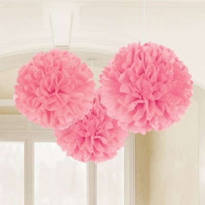 Três pompons de papel cor-de-rosa pendurados em interior iluminado