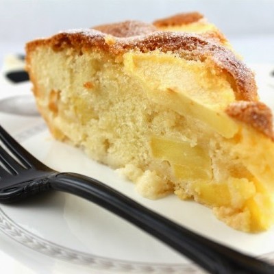 Fatias de bolo com pedaços de maçã num prato branco e garfo preto