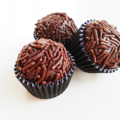 Tres brigadeiros com granulados de chocolate em forminhas pretas