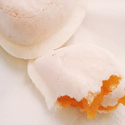 Dois pastéis de nata com recheio e massa folhada sobre papel branco