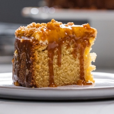 Fatia de bolo amarelo com cobertura caramelizada num prato branco