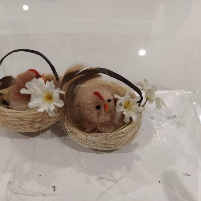 Dois ninhos decorativos com pássaros artificiais e flores brancas em superfície branca