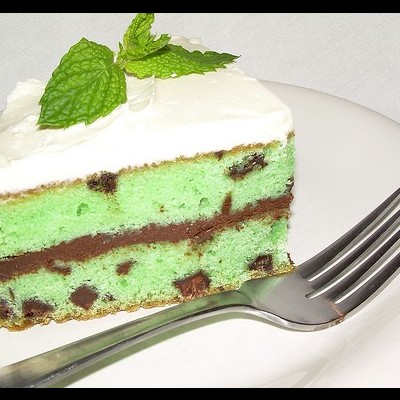 Fatia de bolo verde com chocolate e cobertura branca no prato com garfo