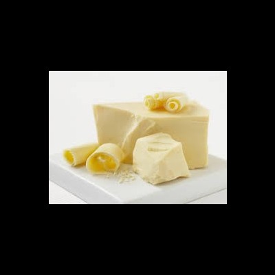 Bloco grande de manteiga amarela com rodelas enroladas de manteiga em superfície branca