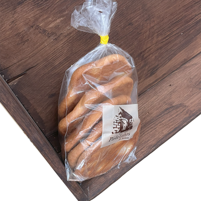 Pão trançado em saco plástico com etiqueta 'Pastelaria' sobre superfície madeira