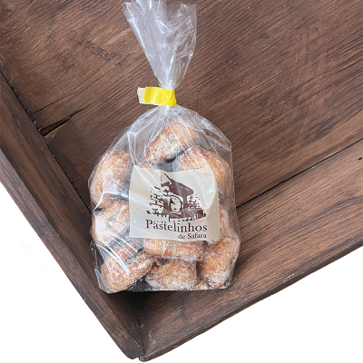 Saco transparente com pastelinhos açucarados e rótulo 'Pastelinhos de Safari' sobre madeira escura