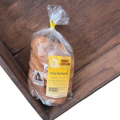 Pacote de tortas Alentejanas embaladas em saco plástico com etiqueta amarela sobre madeira escura