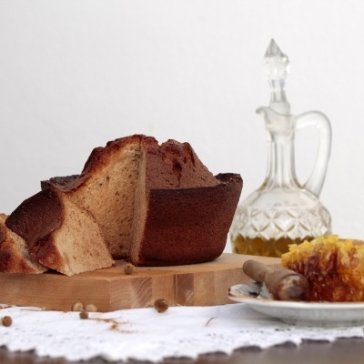 Pão cortado, favo de mel em prato e garrafa de vidro sobre pano branco rendado