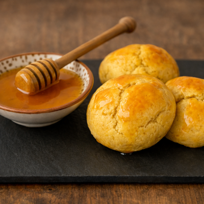 Broinhas de milho douradas com mel em tigela de cerâmica e colher de mel