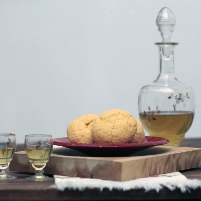 Garrafa de vidro com duas chávenas e bolos sobre tábua de madeira