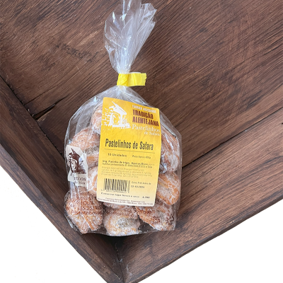 Saco transparente com pastelinhos tradicionais com etiqueta amarela sobre madeira