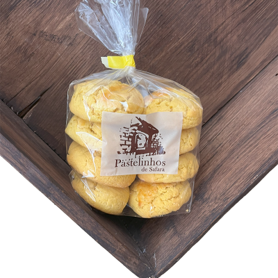 Bolachas amarelas em saco plástico transparente com etiqueta 'Pastelinhos de Safara' sobre madeira
