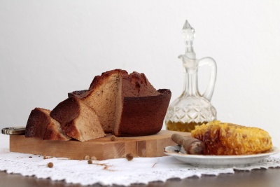 Pão cortado, favo de mel em prato e garrafa de vidro sobre pano branco rendado