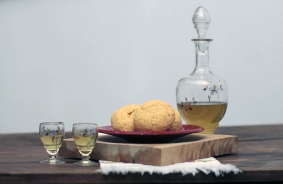 Garrafa de vidro com duas chávenas e bolos sobre tábua de madeira