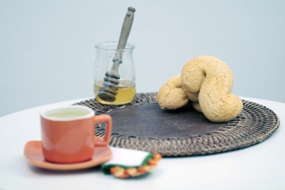 Biscoitos, jarra de mel com colher e chá em conjunto de cerâmica cor de laranja sobre mesa branca