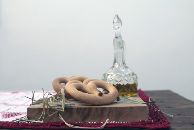 Biscoitos em forma de anel sobre suporte de madeira com tecidos bordados e jarro de vidro ao fundo