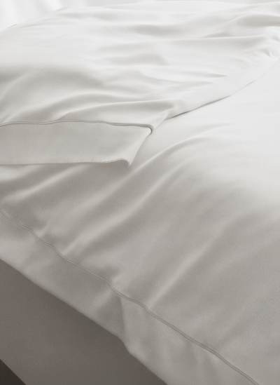 Colcha branca lisa com costura visível numa cama