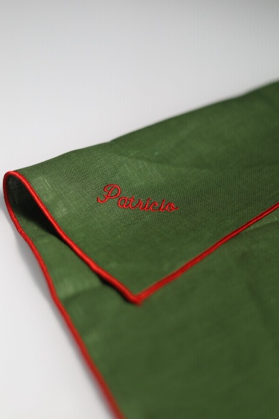 Guardanapo verde com borda vermelha e nome bordado