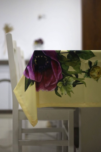 Toalha de mesa amarela com flores coloridas sobre cadeiras brancas