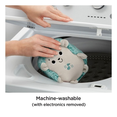 Brinquedo de pelúcia verde e cinzento sendo colocado em máquina de lavar roupa branca