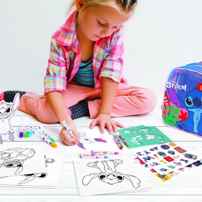 Criança a colorir desenhos do personagem Stitch com mochila ao lado.