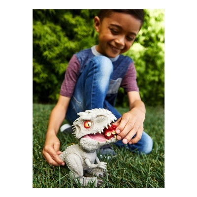 Menino a brincar com figura de dinossauro cinzento no relvado
