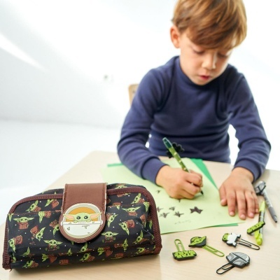 Carteira infantil com padrão Baby Yoda em mesa com menino a desenhar e acessórios