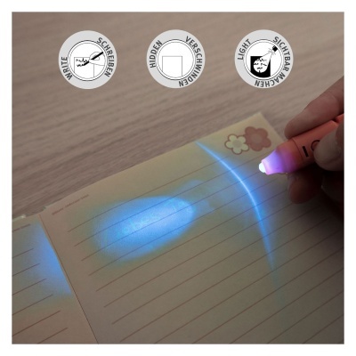 Caneta UV a revelar texto invisível num caderno de folhas creme com linhas