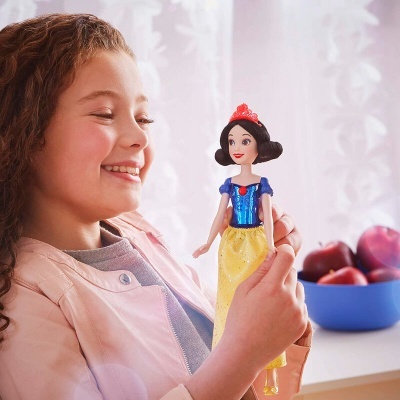 Menina sorridente segurando boneca da Branca de Neve com vestido azul e amarelo