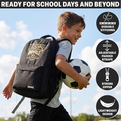Criança com mochila preta Victory Royale Fortnite segurando bola de futebol ao ar livre