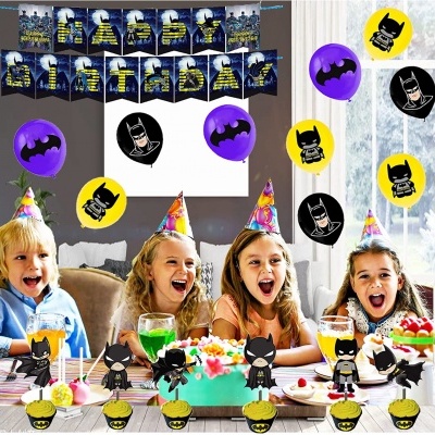 Decoração de festa da Batman com balões coloridos, faixa decorativa e figuras de cupcakes com personagens Batman e crianças sentadas à mesa