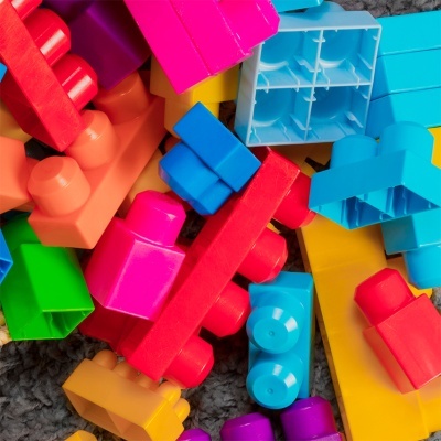 Blocos de construção coloridos em plástico sobre superfície texturada cinzenta
