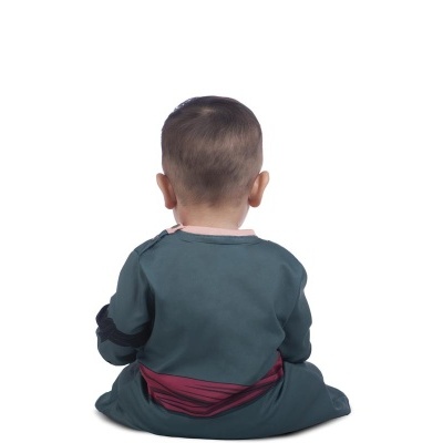 Bébé sentado de costas com pijama verde com detalhes vermelhos