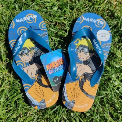 Chinelos de praia azuis com estampa Naruto e etiqueta na relva