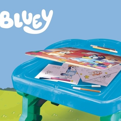 Mesa e cadeira infantil de plástico com desenhos e lápis em fundo azul e verde