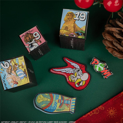 Cubos ilustrados, patch bordado Asterix e pins coloridos em superfície verde