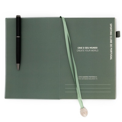 Caderno verde aberto com fita de cetim e caneta preta