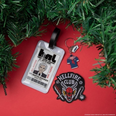 Crachá, chaveiro e patch com temas de fantasia sobre fundo vermelho e ramos verdes.