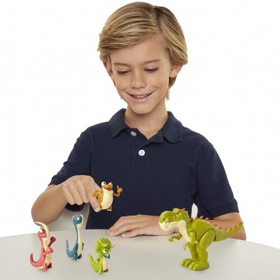 Menino brincando com figuras de dinossauros coloridos numa mesa branca.