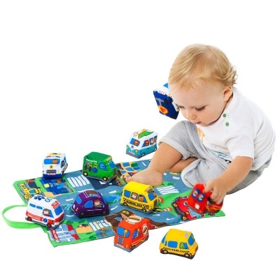 Criança a brincar com carros de brinquedo em tecido colorido com estrada e sinais