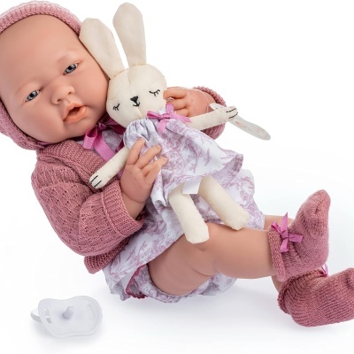 Boneca bebé com roupa rosa segurando um coelho de peluche lilás e chupeta branca
